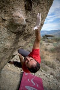 climber reaching for a hold on a boulder